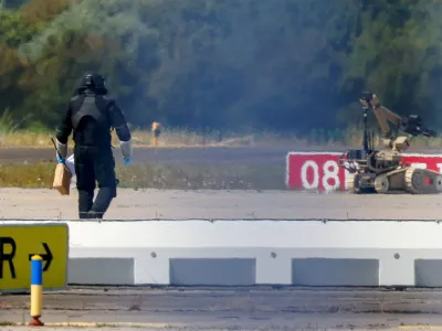 FILE PHOTO: A police officer in protective clothing walks next to an explosive-disarming robot (EOD) at Leipzig/Halle Airport in Schkeuditz, Germany, August 5, 2026, after the police said explosives experts examined a drone found near a runway, and after a DHL cargo aircraft hit an unknown object as it was climbing away from the airport overnight, prompting an unscheduled landing in Hanover, according to a source familiar with the incident. REUTERS/Axel Schmidt/File Photo