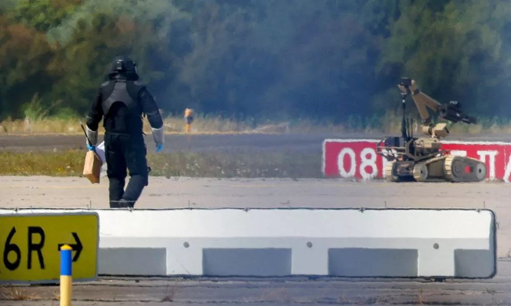 FILE PHOTO: A police officer in protective clothing walks next to an explosive-disarming robot (EOD) at Leipzig/Halle Airport in Schkeuditz, Germany, August 5, 2026, after the police said explosives experts examined a drone found near a runway, and after a DHL cargo aircraft hit an unknown object as it was climbing away from the airport overnight, prompting an unscheduled landing in Hanover, according to a source familiar with the incident. REUTERS/Axel Schmidt/File Photo