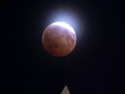 A lunar eclipse of the moon is seen through light clouds above the Washington Monument in Washington, Thursday, Aug. 27, 2026. (AP Photo/Cliff Owen)