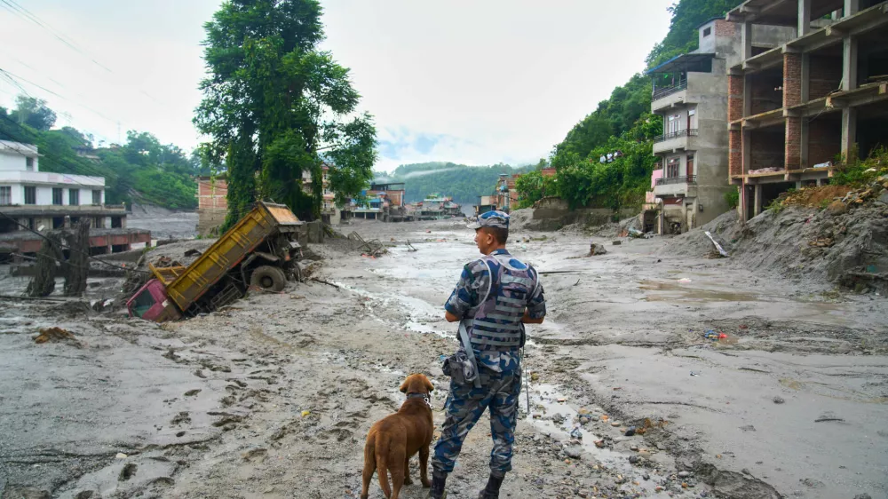 A policeman with a sniffer dog looks at the damage in the aftermath of flash floods in Devighat in the Nuwakot district in Nepal, Thursday, Aug 27, 2026. (AP Photo/Niranjan Shrestha)