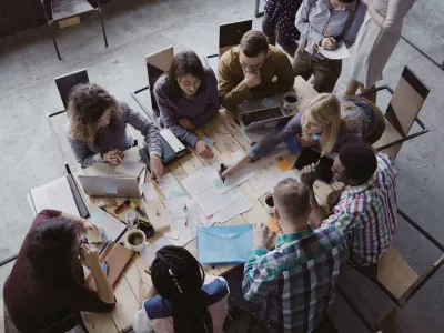Top view of creative business team sitting at the table at loft office and working. Woman manager brings the document to mixed race group of people. Colleagues discussing the project.