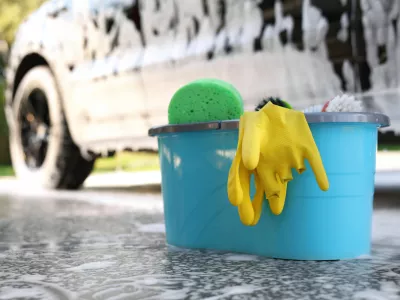 Car cleaning supplies and auto covered with foam outdoors