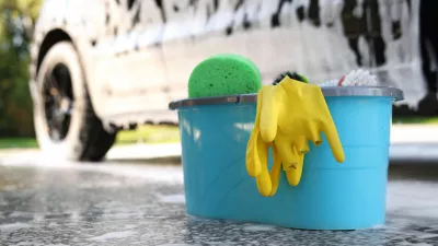 Car cleaning supplies and auto covered with foam outdoors