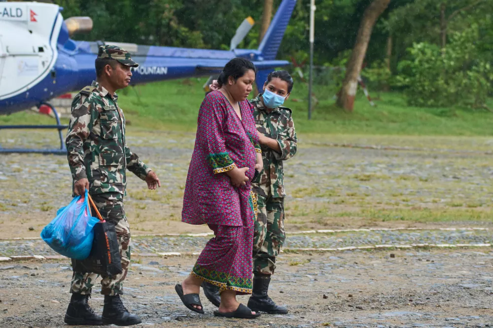 Nepalese army personnel help a pregnant woman reach a helicopter before she is airlifted to a hospital in Kathmandu from Maithali Barracks in Nuwakot district, Nepal, Friday, Aug. 28, 2026. (AP Photo/Niranjan Shrestha)