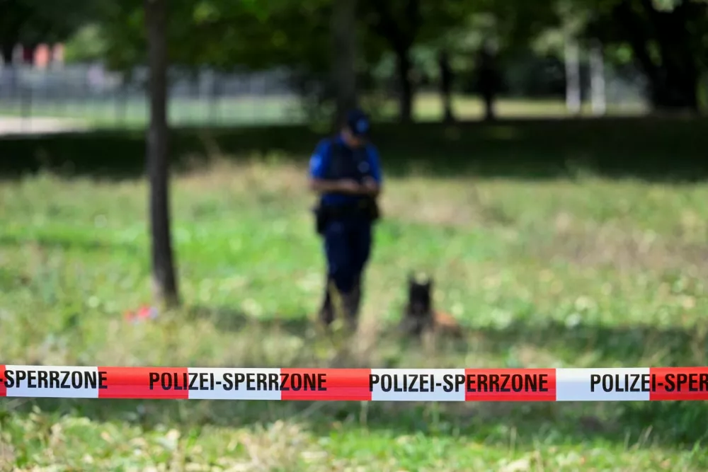 A police officer stands with the dog next to barricade tape, near the site of a deadly shooting at a rave party, according to the police, at Schachen in Aarau, Switzerland, August 30, 2026. REUTERS/Romina Amato