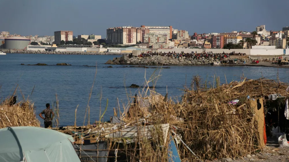 Makeshift shelters used by migrants line the coast as a crowd gathers on a breakwater in Ceuta, Spain, August 15, 2026. REUTERS/Maria Alejandra Cardona