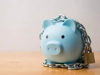 Blue piggy bank locked with chain and padlock on wooden table white wall background. Savings money protection, money management, scammer prevention, safety deposit account, financial, economy concept.