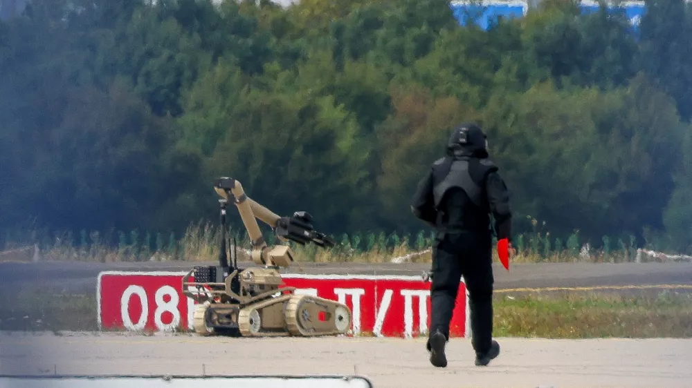 FILE PHOTO: A police officer in protective clothing walks next to an explosive-disarming robot (EOD) at Leipzig/Halle Airport in Schkeuditz, Germany, August 5, 2026, after the police said explosives experts examined a drone found near a runway, and after a DHL cargo aircraft hit an unknown object as it was climbing away from the airport overnight, prompting an unscheduled landing in Hanover, according to a source familiar with the incident. REUTERS/Axel Schmidt/File Photo