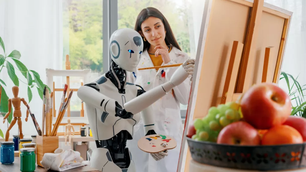 Creative AI robot learning how to paint on canvas in the art studio, a young teacher is training her