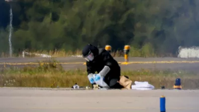 FILE PHOTO: A police officer in protective clothing works at Leipzig/Halle Airport in Schkeuditz, Germany, August 5, 2026, after the police said explosives experts examined a drone near a runway, and after a DHL cargo aircraft hit an unknown object as it was climbing away from the airport overnight, prompting an unscheduled landing in Hanover, according to a source familiar with the incident. REUTERS/Axel Schmidt/File Photo