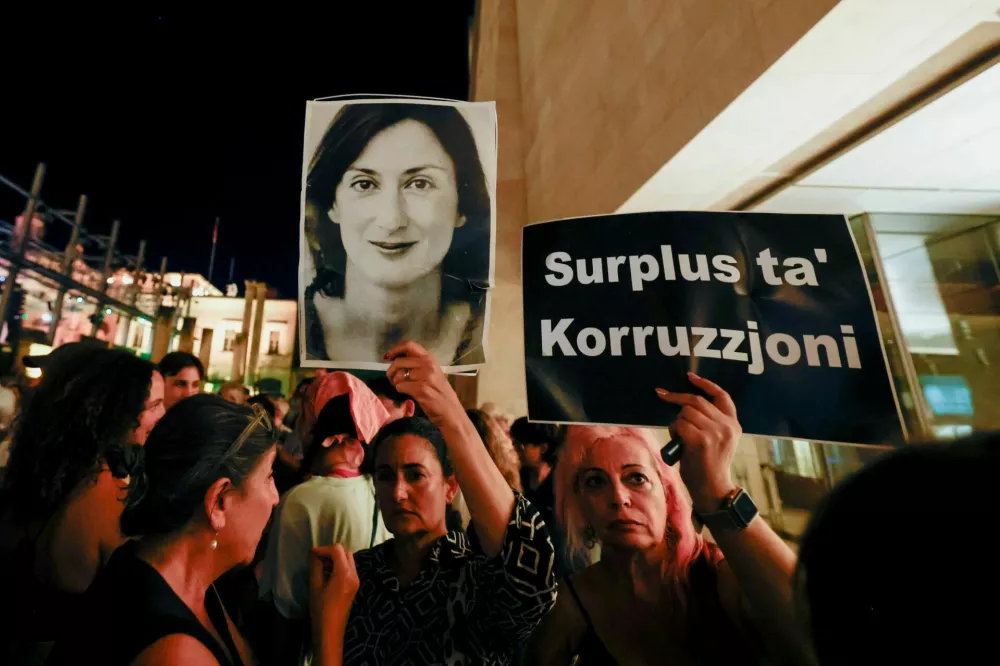 A sign reading "A surplus of corruption" and a portrait of investigative journalist Daphne Caruana Galizia is held up by people protesting outside Parliament House after Maltese businessman Yorgen Fenech was acquitted of conspiracy and complicity to murder her in 2017, in Valletta, Malta, September 2, 2026. REUTERS/Darrin Zammit Lupi