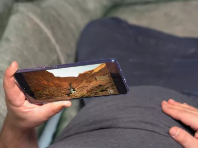 Man lying on couch and watching video about canyon valley in high definition through Huawei Mate 20 X smartphone. Display shows extremely nice and soft image Kyiv, Ukraine 15th of June 2019
