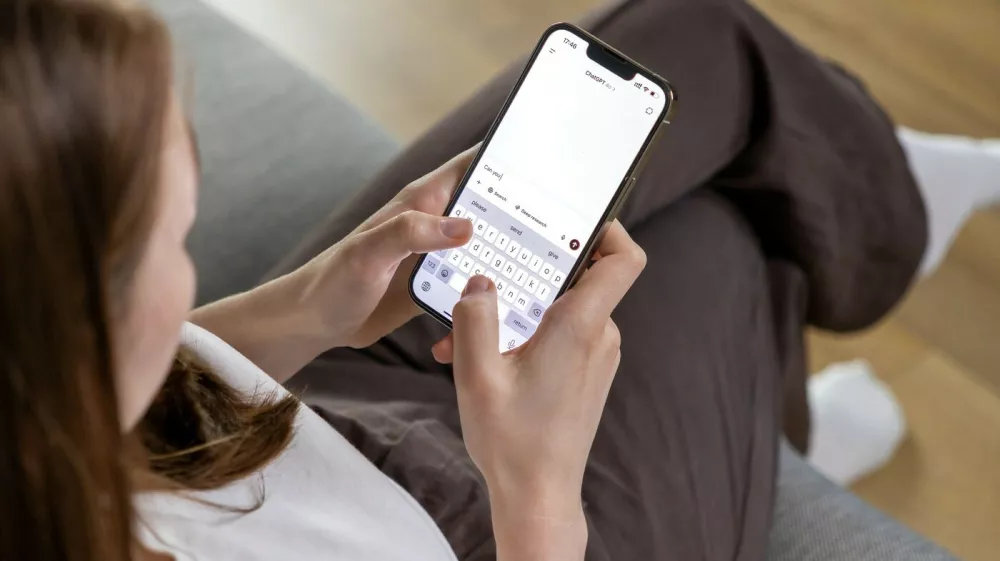 Poznan, Poland &ndash; April 14, 2025: A woman holding a smartphone and typing a question to the ChatGPT AI assistant, using a conversational text interface on the app,Image: 991604543, License: Royalty-free, Restrictions:, Model Release: no 