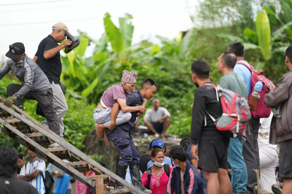 Balaram Gajurel is carried by a policeman on his back after getting transported on a zip line constructed to transport stranded citizens across the Trishuli river following flash floods in Nepal's Nuwakot district, Thursday, Sept. 3, 2026. (AP Photo/Rajesh Kumar Singh)