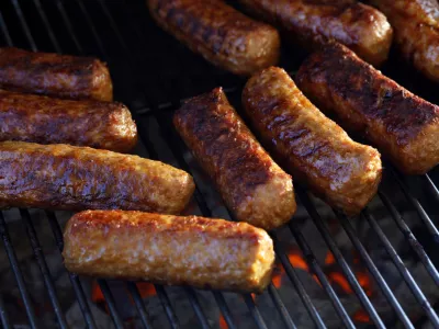 Close-up of roasted cevapi, cevapcici on the grill over glowing charcoal, traditional Balkan meat sausages on the bbq.