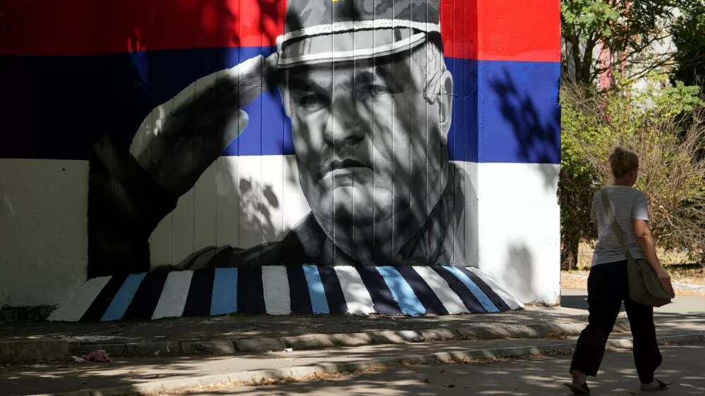 A woman walks by a mural that shows former Bosnian Serb wartime general Ratko Mladic in Belgrade, Serbia, Wednesday, Sept. 2, 2026. (AP Photo/Darko Vojinovic)