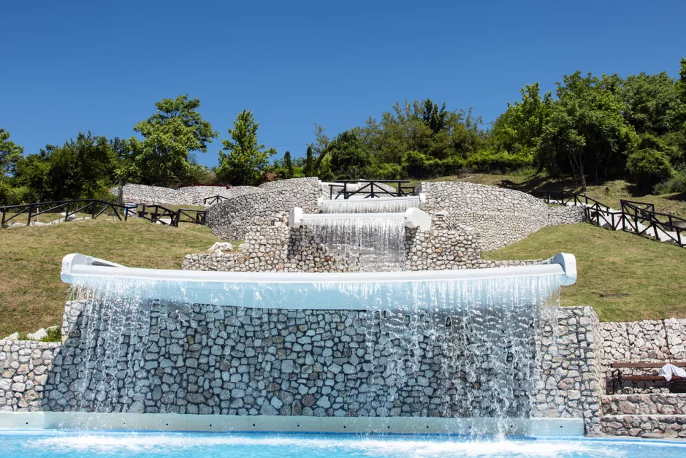 Close up steady shot of crystal clear water splashing and flowing down beautiful stone waterfalls at Pannonian Lakes complex in Tuzla.