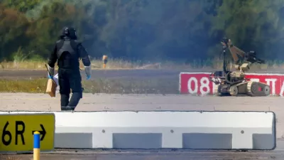FILE PHOTO: A police officer in protective clothing walks next to an explosive-disarming robot (EOD) at Leipzig/Halle Airport in Schkeuditz, Germany, August 5, 2026, after the police said explosives experts examined a drone found near a runway, and after a DHL cargo aircraft hit an unknown object as it was climbing away from the airport overnight, prompting an unscheduled landing in Hanover, according to a source familiar with the incident. REUTERS/Axel Schmidt/File Photo