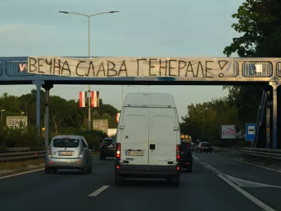 Cars pass under a pedestrian bridge with a banner on it reading: "Eternal glory, General! (former Bosnian Serb wartime general Ratko Mladic)" in Belgrade, Serbia, Thursday, Sept. 3, 2026. (AP Photo/Darko Vojinovic)