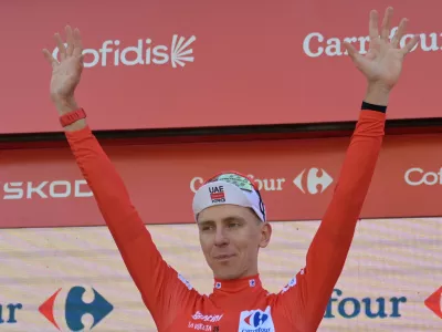 Slovenia's Tadej Pogacar, wearing the overall leader's red jersey celebrates on the podium after the second stage of the La Vuelta cycling race, with start in Monaco and finish in Manosque, France, Sunday, Aug. 23, 2026. (AP Photo/Philippe Magoni)