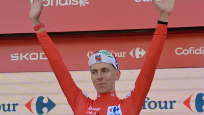 Slovenia's Tadej Pogacar, wearing the overall leader's red jersey celebrates on the podium after the second stage of the La Vuelta cycling race, with start in Monaco and finish in Manosque, France, Sunday, Aug. 23, 2026. (AP Photo/Philippe Magoni)
