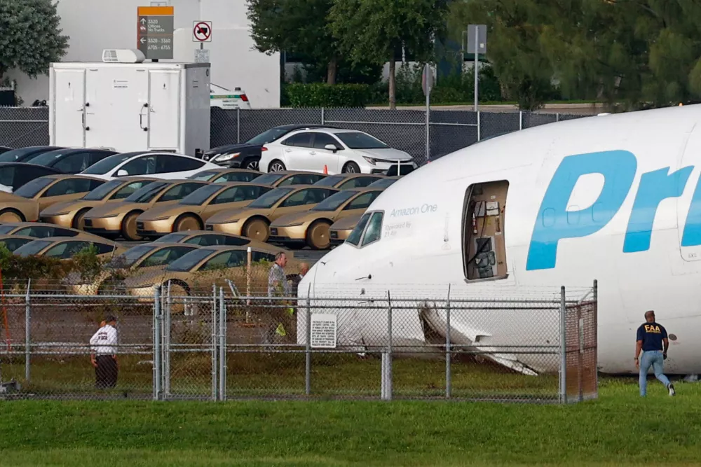 Tesla Cybercabs are parked in a lot next to where a crashed Amazon Prime Air cargo plane came to rest, where airport officials said it overran a runway at Miami International Airport, in Miami, Florida, U.S., September 6, 2026. REUTERS/Marco Bello