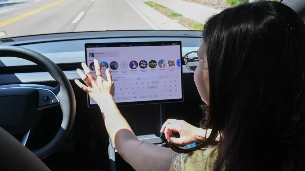 Tampa Bay Times reporter Camila Gomez reaches toward the touchscreen display to select music while riding in a Tesla Robotaxi in Tampa, Florida, on August 14, 2026. Gomez was testing the autonomous vehicle service as part of a firsthand account for the Tampa Bay Times, navigating the car's center-mounted infotainment screen while the vehicle operated without a human driver on a public road.,Image: 1126106139, License: Rights-managed, Restrictions: *** World Rights *** US Newspapers Out *** NO TV, VIDEO, FILM ***, Model Release: no 