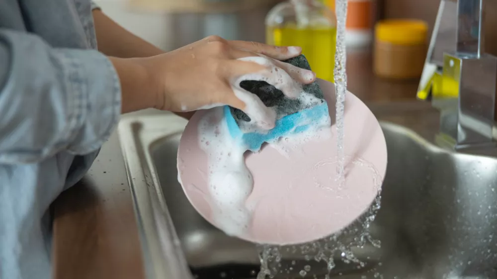 Close up of female hands cleaning a dirty plate / Foto: Yacobchuk