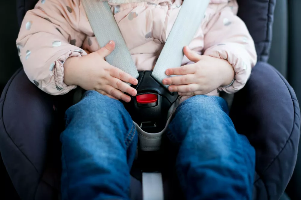 Hands of a little girl lie on the seat belt buckle of a child seat. Close-up,Image: 538187485, License: Royalty-free, Restrictions:, Model Release: yes