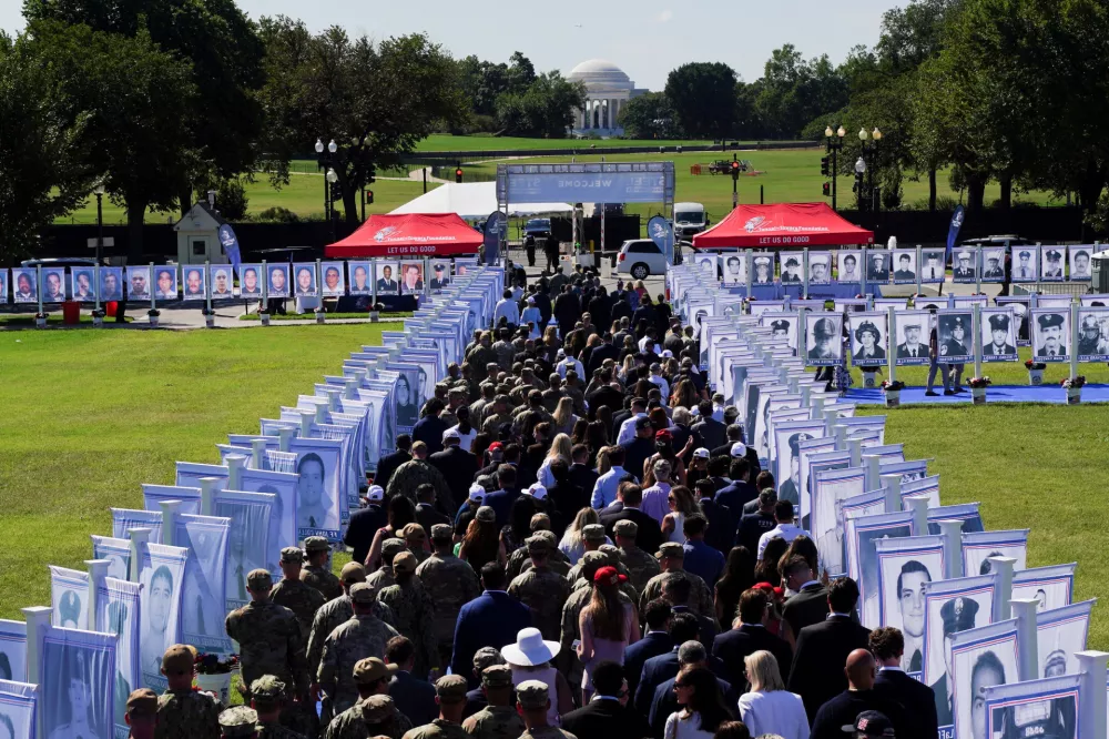 People walk past photographs of victims who died in the September 11, 2001, attacks, on the day of the Steel Across America event featuring a 21-foot steel beam recovered from the World Trade Centre South Tower, on the Ellipse near the White House in Washington, D.C., U.S., September 8, 2026. REUTERS/Nathan Howard