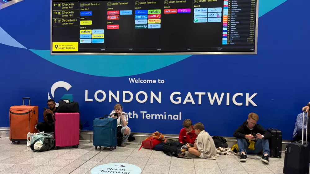 Passengers at Gatwick Airport's South Terminal sit after flights were cancelled because of a technical issue in Britain's air traffic control system Tuesday, Sept. 8, 2026, in Crawley, south of London. (Jordan Pettitt/PA via AP)