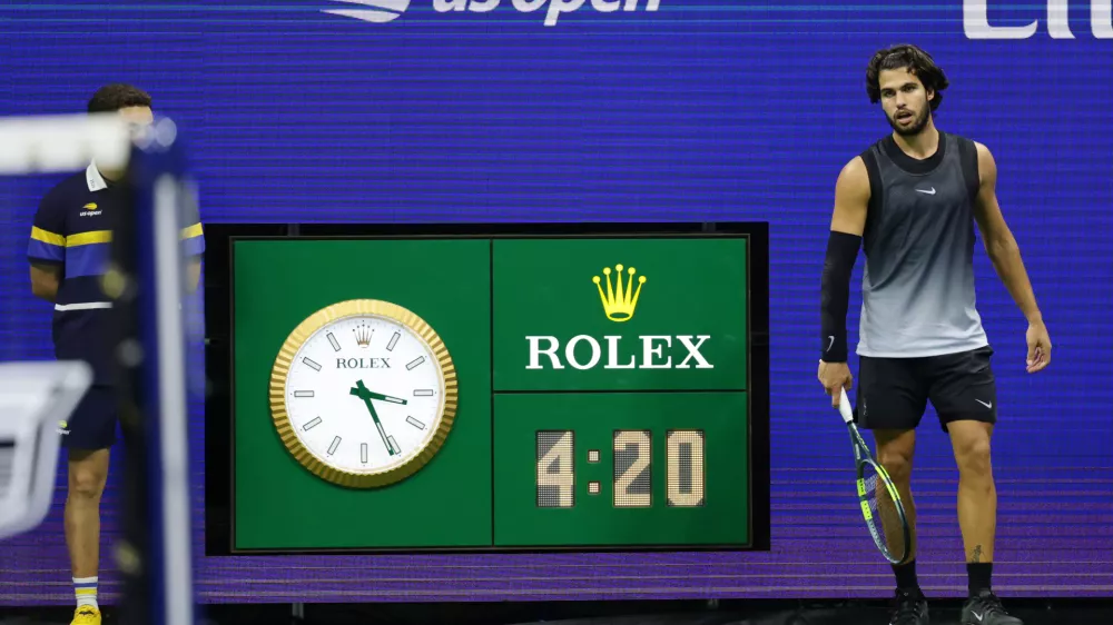 The clock reads 3:21 a.m. as Carlos Alcaraz, of Spain, plays in the fifth set against Ben Shelton, of the United States, during the quarterfinal round of the U.S. Open tennis championships, early Wednesday, Sept. 9, 2026, in New York. (AP Photo/Adam Hunger)