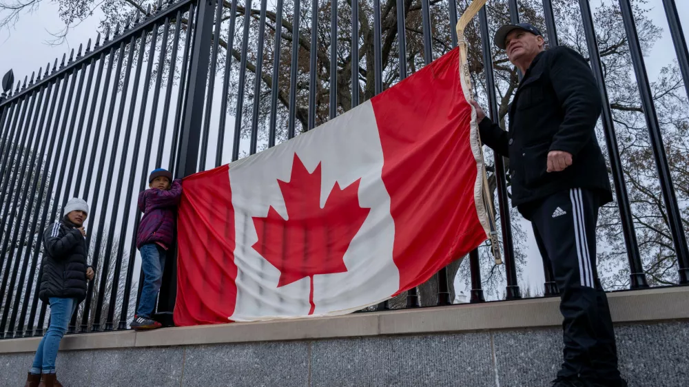 FILE - From right, Toronto residents Douglas Bloomfield, his son Phoenix and wife Ame, who are on vacation in Washington, hold a Canadian flag and an ice hockey stick to show their support for Canada regarding trade tariffs, in front of the White House in Washington, March 13, 2025. (AP Photo/Ben Curtis, File)