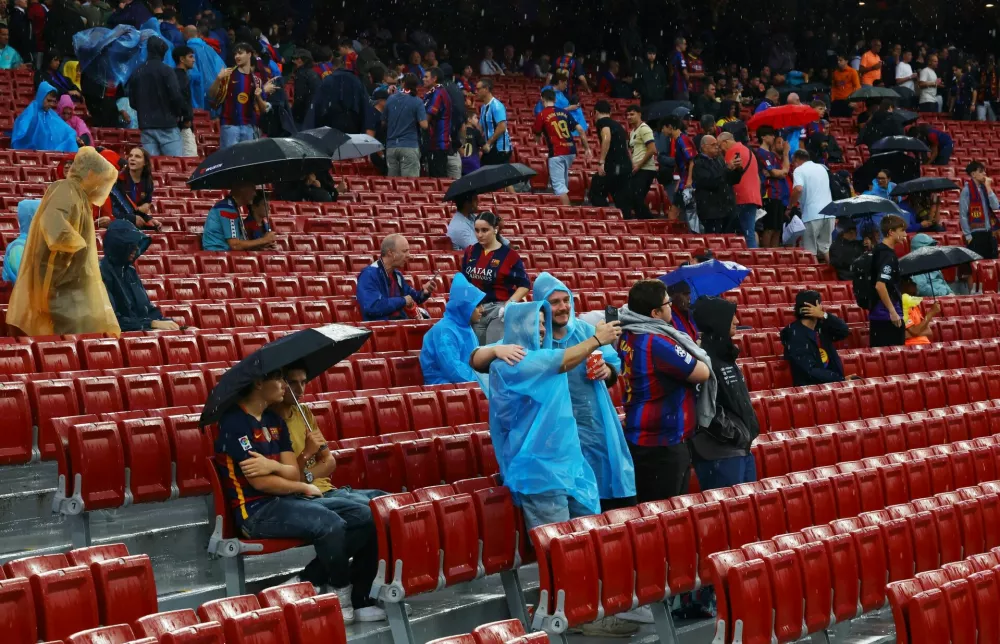 Soccer Football - UEFA Champions League - FC Barcelona v Feyenoord - Spotify Camp Nou, Barcelona, Spain - September 9, 2026 Fans shield themselves from the rain inside the stadium before the match REUTERS/Albert Gea