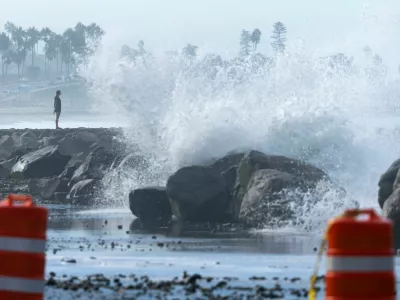 A person stands on a jetty as waves break over riprap and onto a beach parking lot in Carlsbad, California, U.S., September 8, 2026. REUTERS/Mike Blake