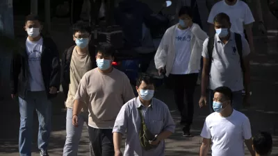 Commuters wearing face masks walk along a street during the morning rush hour in Beijing, Tuesday, May 23, 2023. (AP Photo/Mark Schiefelbein)