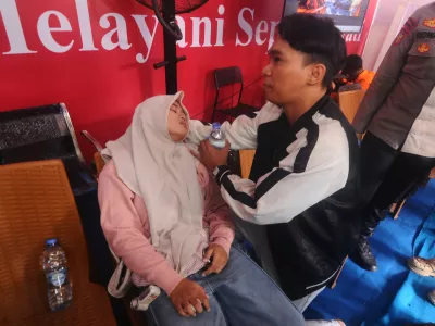 A woman loses consciousness upon learning that the name of a relative is on the passenger list of a ferry overturned in bad weather in the Java Sea, at the rescuers command center in Banjarmasin, South Kalimantan, Indonesia, Sunday, Sept. 13, 2026. (AP Photo/Iman Satria)