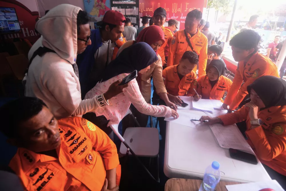 People look for the names of their family members on a passenger list after a ferry overturned in bad weather in the Java Sea, at the rescuers command center in Banjarmasin, South Kalimantan, Indonesia, Sunday, Sept. 13, 2026. (AP Photo/Iman Satria)