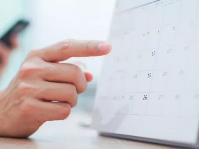 close up on employee man hand using finger pointing schedule (timetable) on calendar to make appointment meeting or manage timetable each day, life balance concept