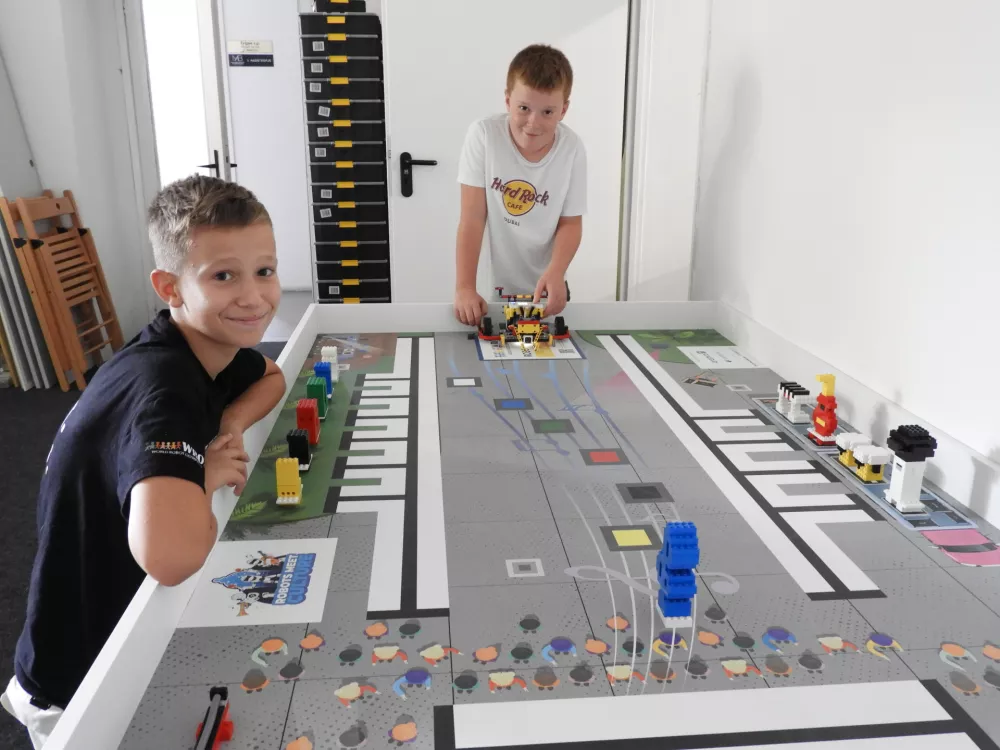 Najmlaj&scaron;a, enajstletna tekmovalca Žiga Ga&scaron;perič Ro&scaron; in Maks Železnik, navdu&scaron;eno pokažeta, kaj njun robot že zmore in česa &scaron;e ne, ko pa mora urediti vse potrebno za koncert. Prinesti mikrofon na pravo mesto, ga povezati z ojačevalcem, posortirati lučke in &scaron;e marsikaj mora postoriti, predvsem pa v pravem vrstnem redu. / Foto: Katja Petrovec 