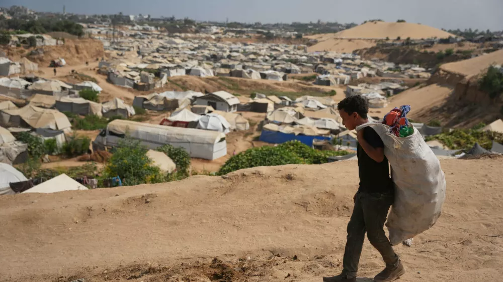 A Palestinian boy leaves a garbage dump after collecting combustible materials to use as fuel for cooking due to a shortage of cooking gas, in Deir al-Balah, central Gaza Strip, Saturday, Aug. 22, 2026. (AP Photo/Abdel Kareem Hana)