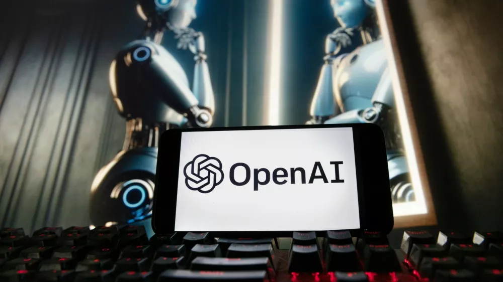 FILE - The OpenAI logo is displayed on a cellphone with an image on a computer monitor generated by ChatGPT's Dall-E text-to-image model, Dec. 8, 2023, in Boston. (AP Photo/Michael Dwyer, File)