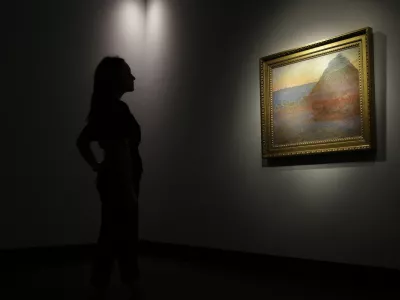 A member of staff poses for the media next to a work of art by Claud Mont entitled ' Merle' (Granistack), 1891, at Christie's auction house in London, Monday, Oct. 24, 2016. The painting is to be sold in New York on Nov. 16, with an estimated value of 45 million pounds (55 million US$). (AP Photo/Alastair Grant)