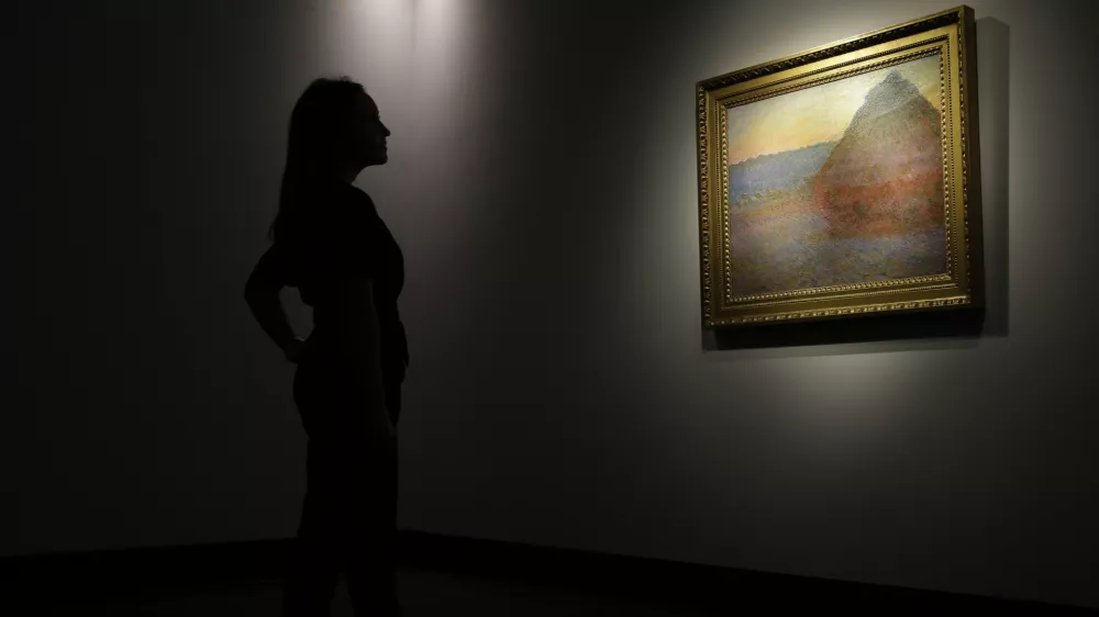 A member of staff poses for the media next to a work of art by Claud Mont entitled ' Merle' (Granistack), 1891, at Christie's auction house in London, Monday, Oct. 24, 2016. The painting is to be sold in New York on Nov. 16, with an estimated value of 45 million pounds (55 million US$). (AP Photo/Alastair Grant)