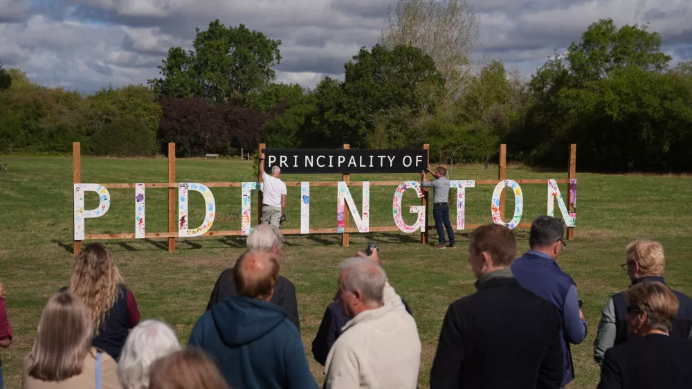 Local residents unveil a "Principality of Piddington" sign in the village of Piddington, Oxfordshire, England, Wednesday, Sept. 16, 2026, after they voted overwhelmingly to become an independent state in a symbolic "referendum". (Joe Giddens/PA via AP)