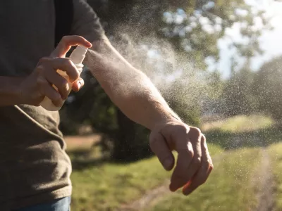 Prevention against mosquito bite during sunny summer day. Man is applying insect repellent on his hand.