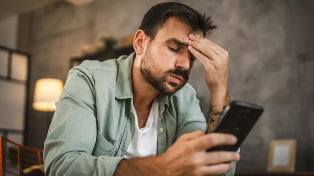 Portrait of adult furious man sit on chair and text sms on cellphone