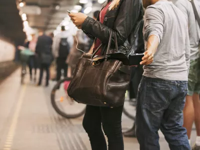 Thief stealing wallet from purse of a woman using mobile phone at the subway station. Pickpocketing at subway station