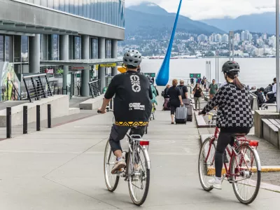 Young active couple in helmets riding on bicycles together on a street of the Vancouver city Canada. Sports, health, activity concept. Travel photo, editorial. July 10,2022