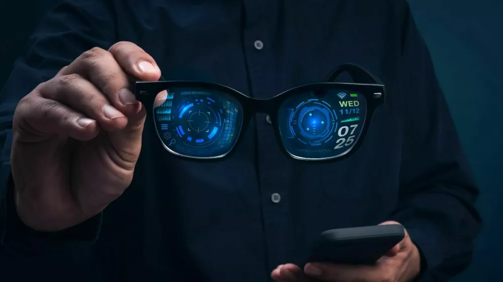 Smart glasses with augmented reality interface showing digital data and futuristic UI holding in businessman hands. Concept of wearable technology, AR innovation, and next-generation smart devices. / Foto: Techa Tungateja